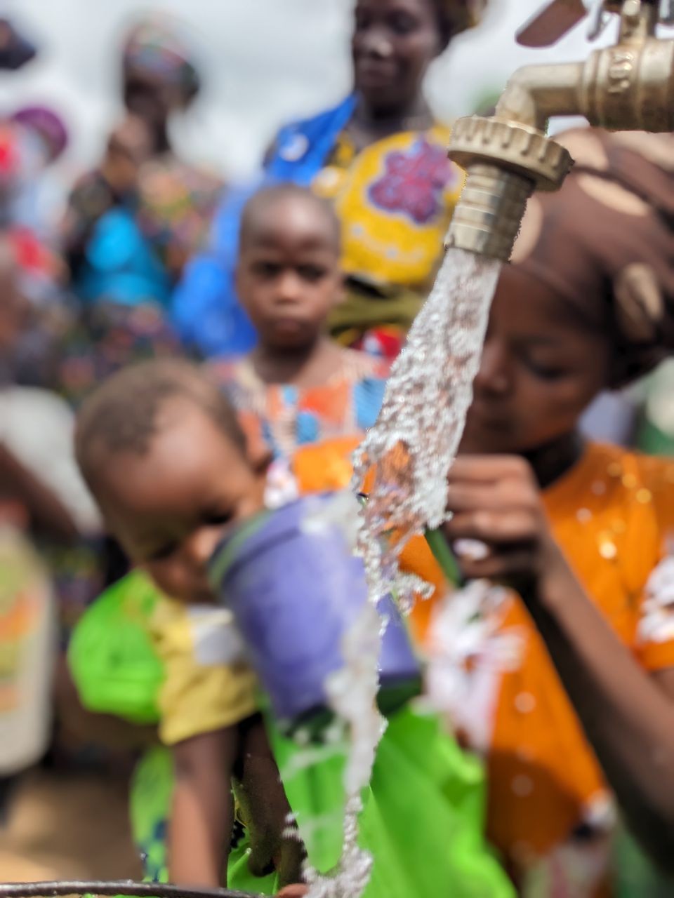 Des habitants d'un village récoltent de l'eau potable à une fontaine alimentée par un forage.